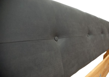 Postel s dřevěným rámem a čalouněným čelem.